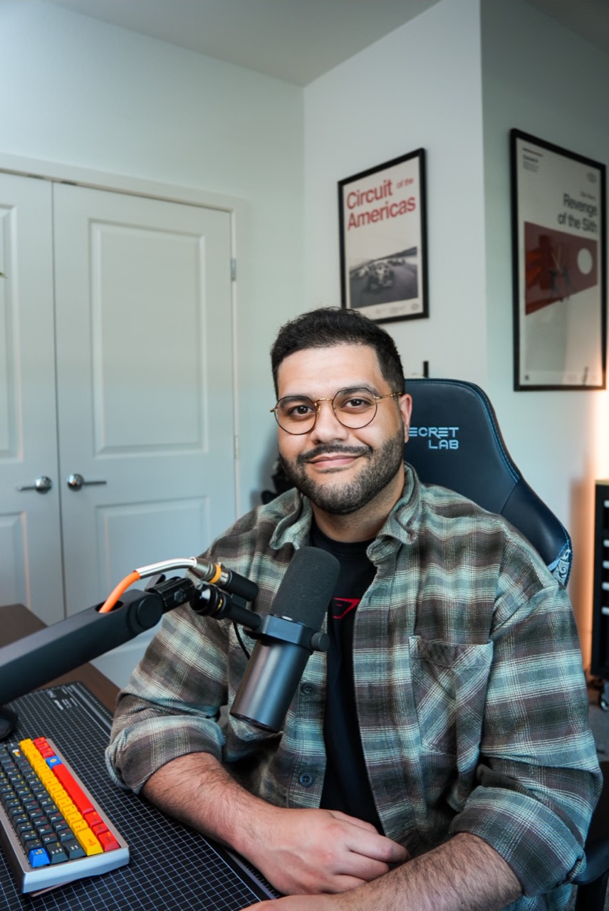 Portrait of me seated at my desk with my microphone and workspace visible