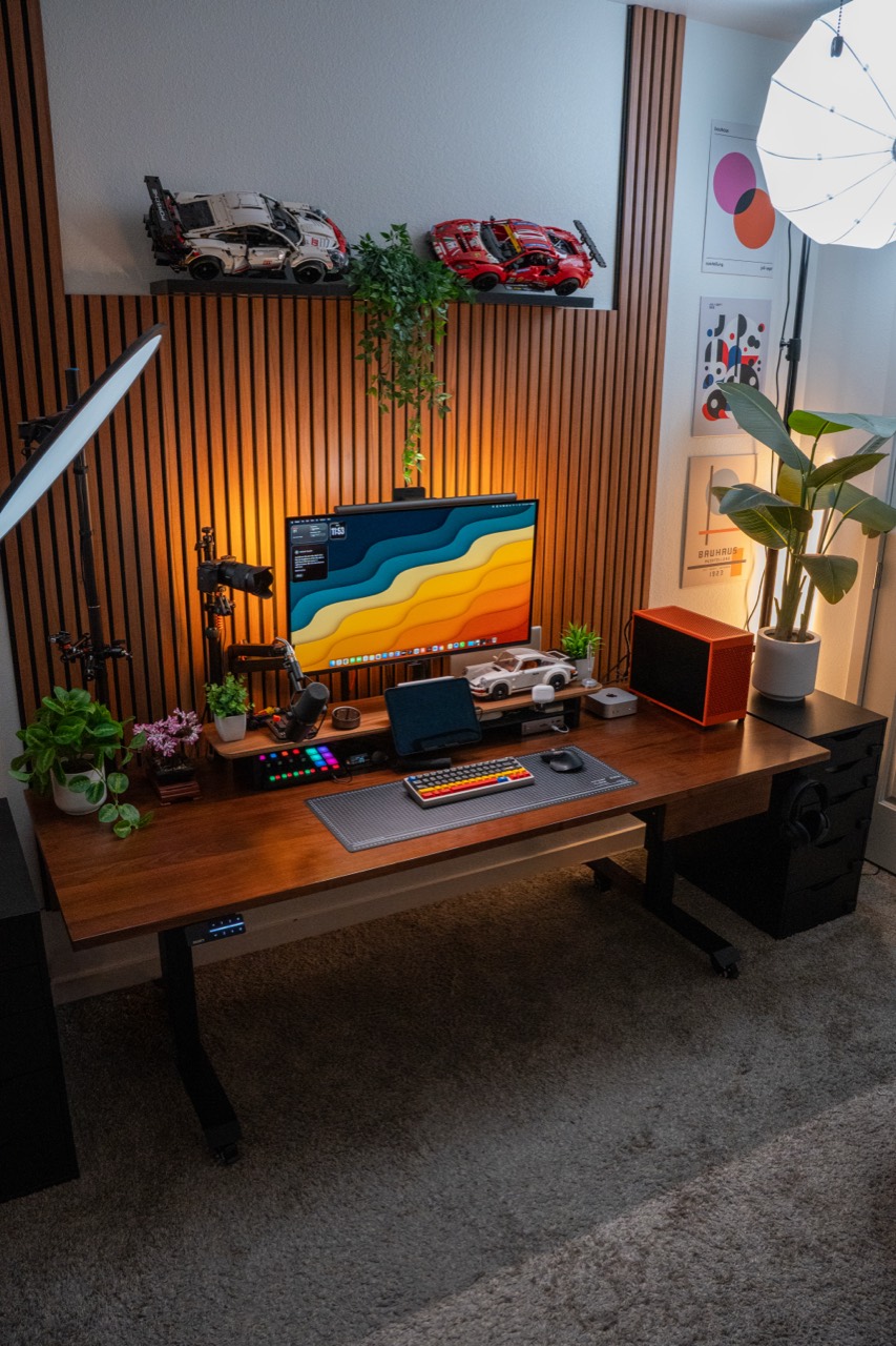 My workspace with a monitor, walnut slat wall, orange PC, plants, desk, and key light